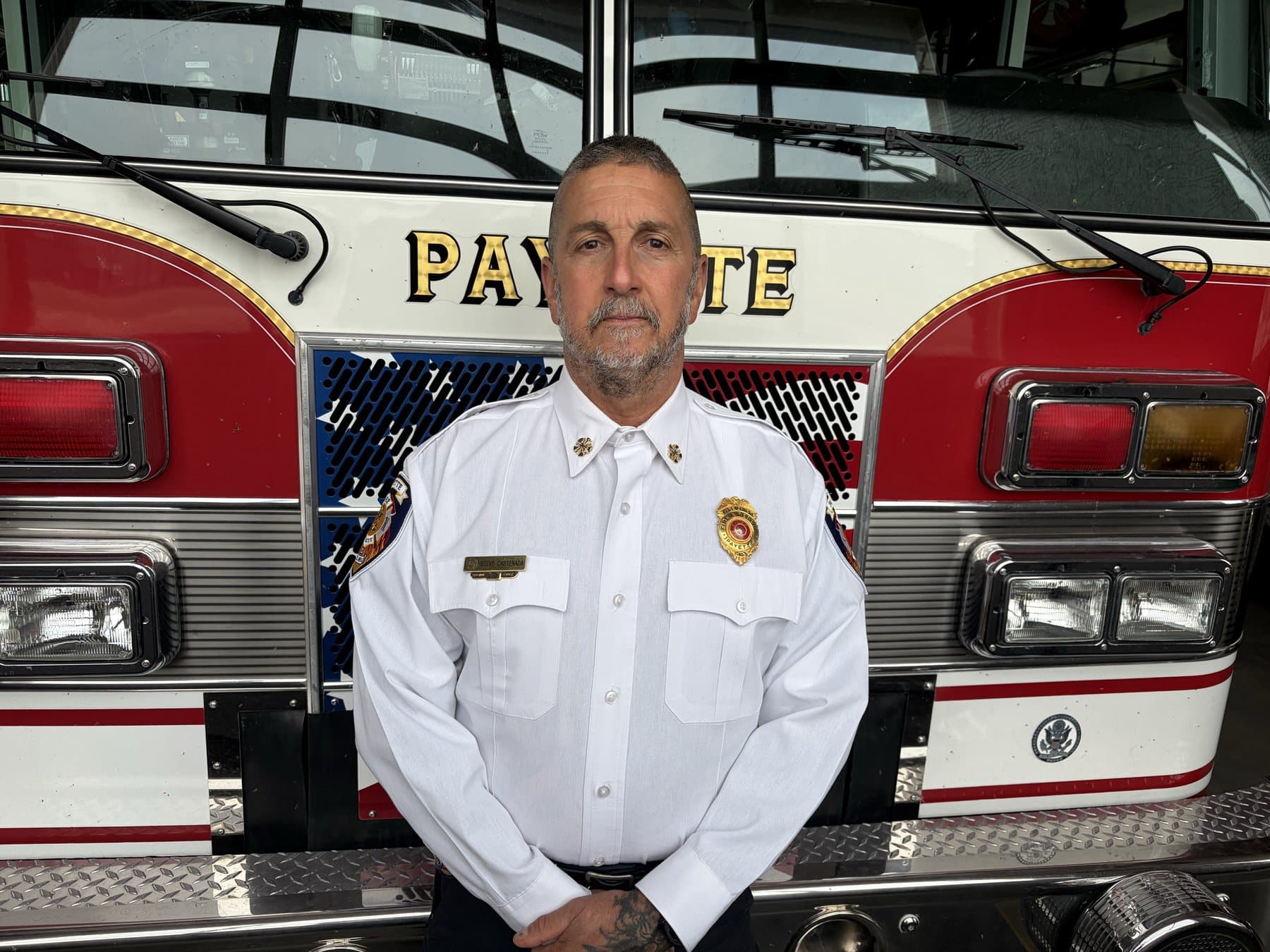Chief Steve Castenada in white dress uniform, standing in front of a Payette fire engine