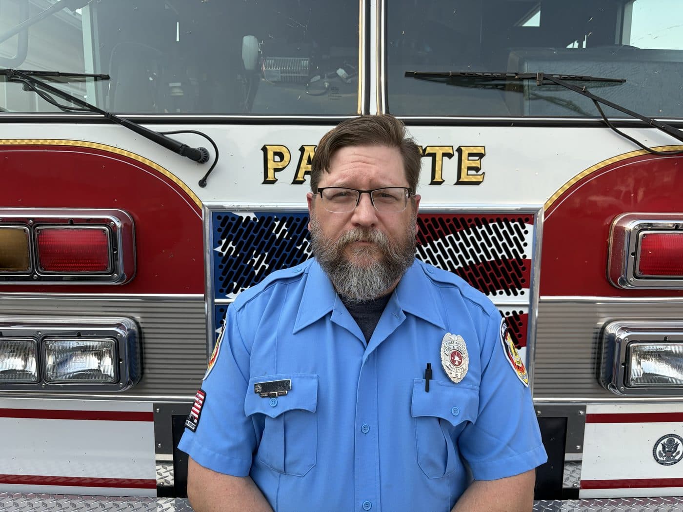 Volunteer Firefighter Chip Hale in uniform, standing in front of a Payette fire engine.