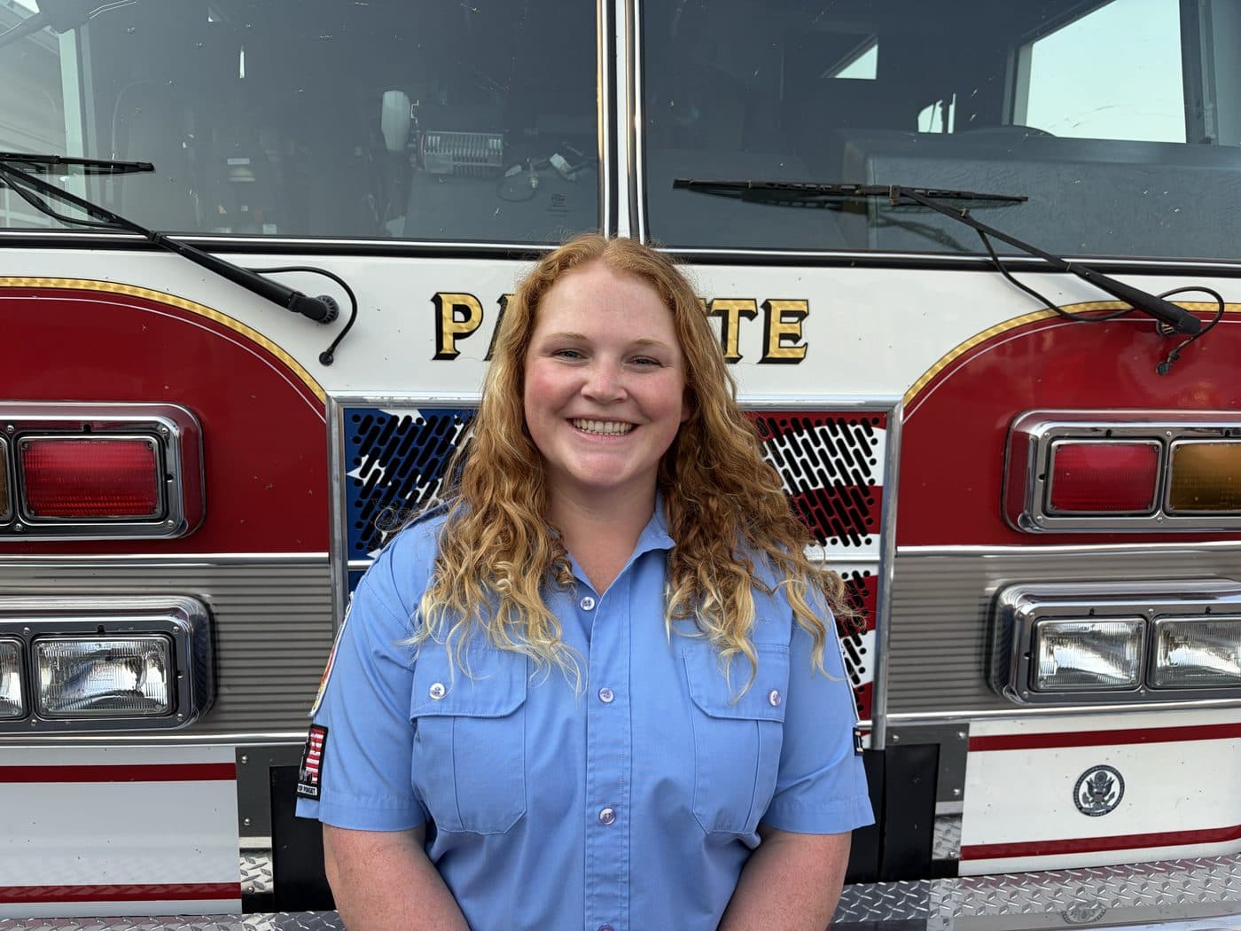 Volunteer Firefighter Mercedes Hoch in uniform, standing in front of a Payette fire engine.