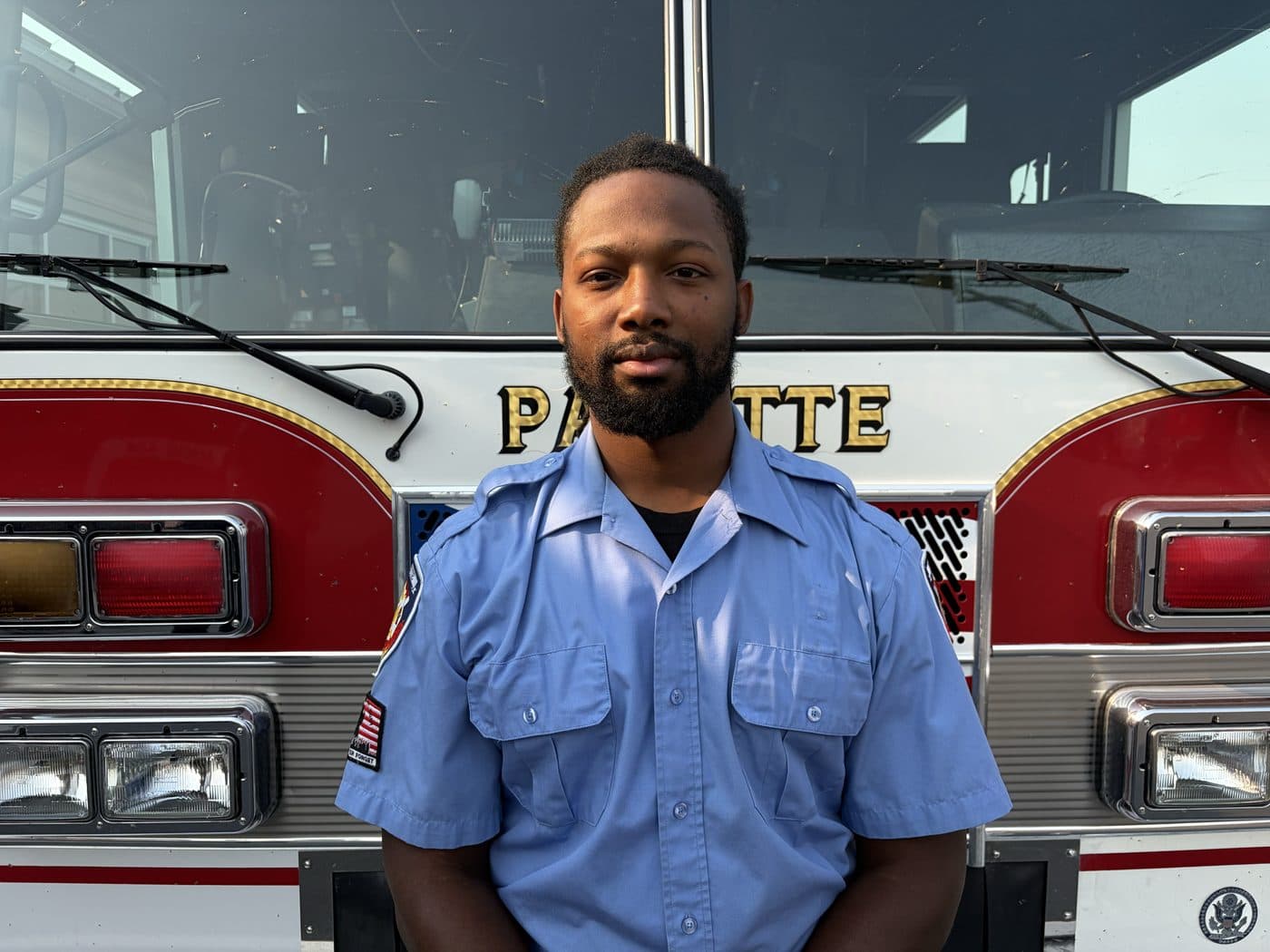Volunteer Firefighter KJ Joiner in uniform, standing in front of a Payette fire engine.