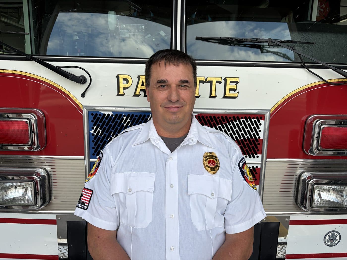 Battalion Chief Doug Kessler in dress uniform, standing in front of a Payette fire engine.