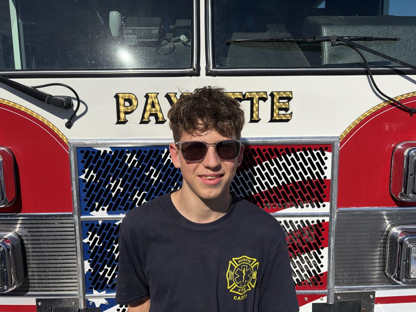 Cadet Firefighter Jaden Klure in a Payette Fire cadet shirt, standing in front of a fire engine.