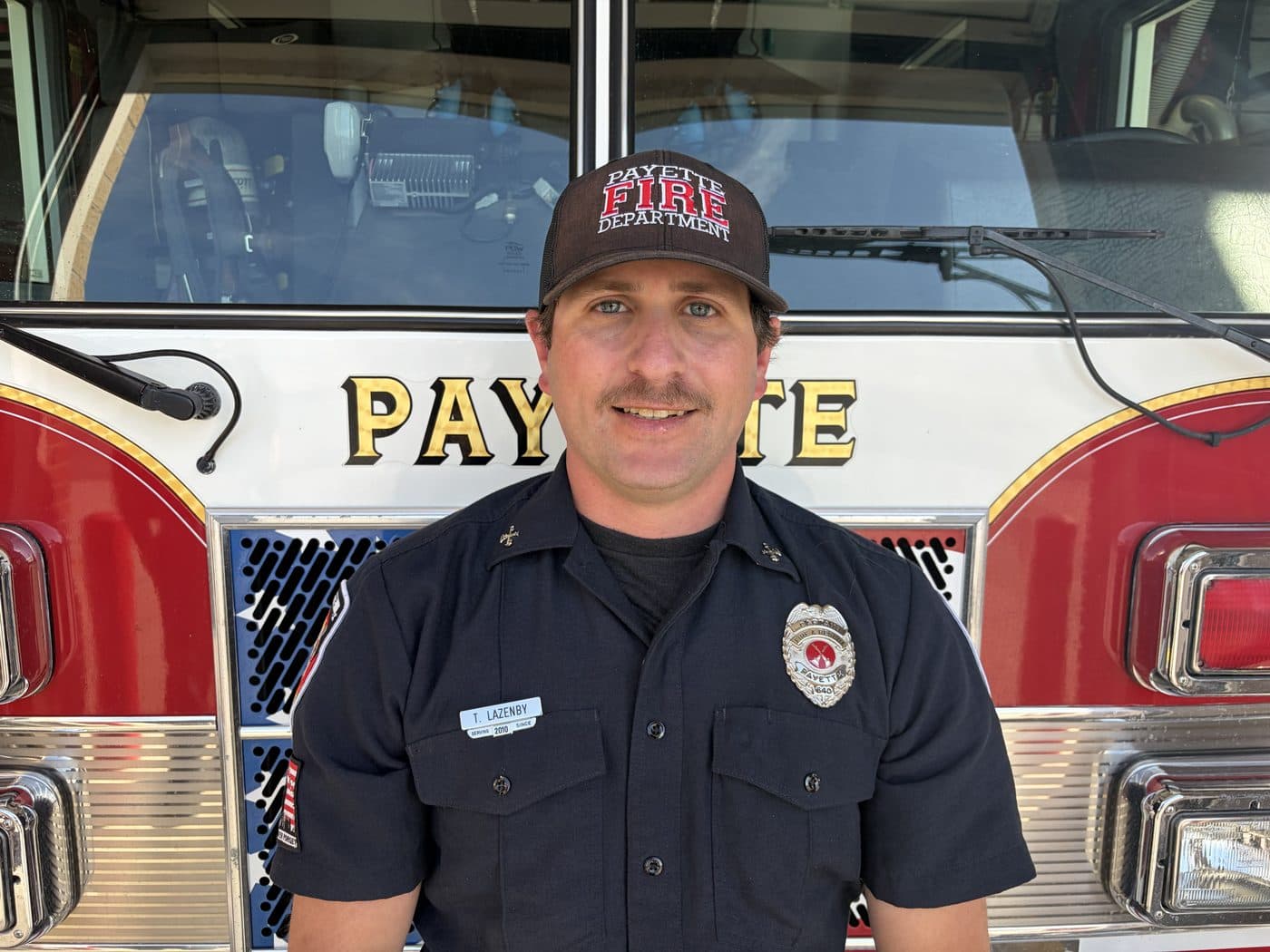 Fire Captain and EMT Tyler Lazenby in uniform, standing in front of a Payette fire engine.