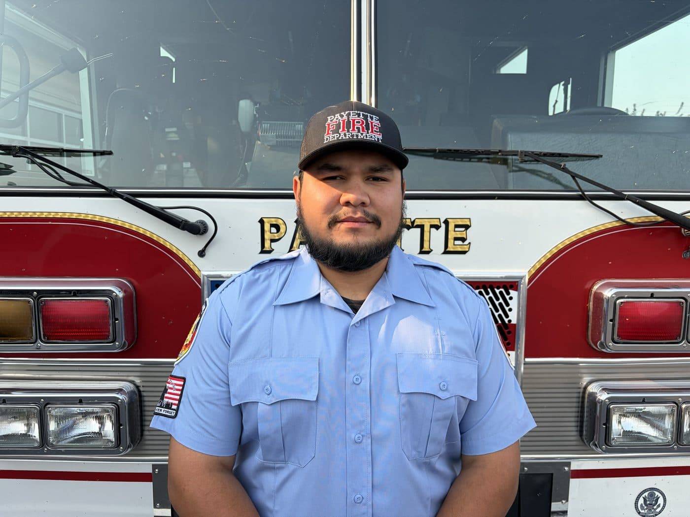 Volunteer Firefighter Gabe Lopez in uniform, standing in front of a Payette fire engine.