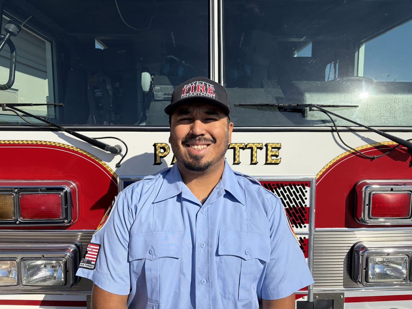 Volunteer Fire Captain Adrian Paz in uniform, standing in front of a Payette fire engine.