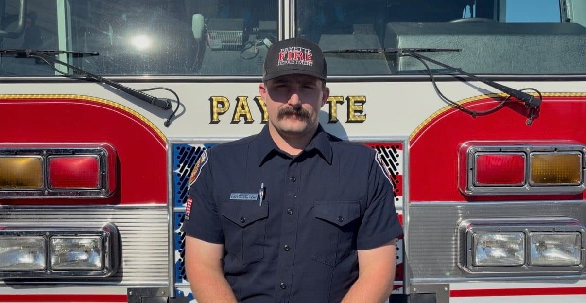 Firefighter and EMT Hunter Pohl in uniform, standing in front of a Payette fire engine.