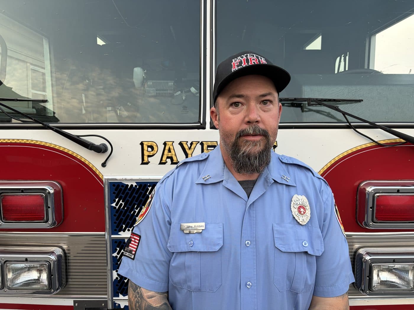 Volunteer Fire Captain Jake Robbins in uniform, standing in front of a Payette fire engine.
