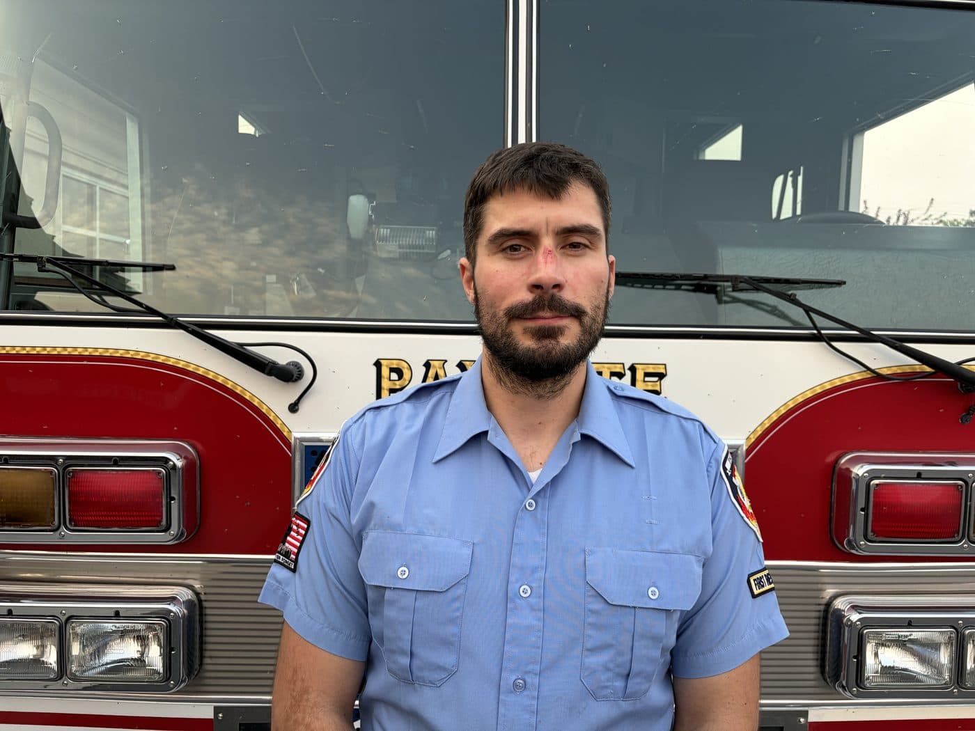 Volunteer Firefighter and EMT Charles Wetzel in uniform, standing in front of a Payette fire engine.
